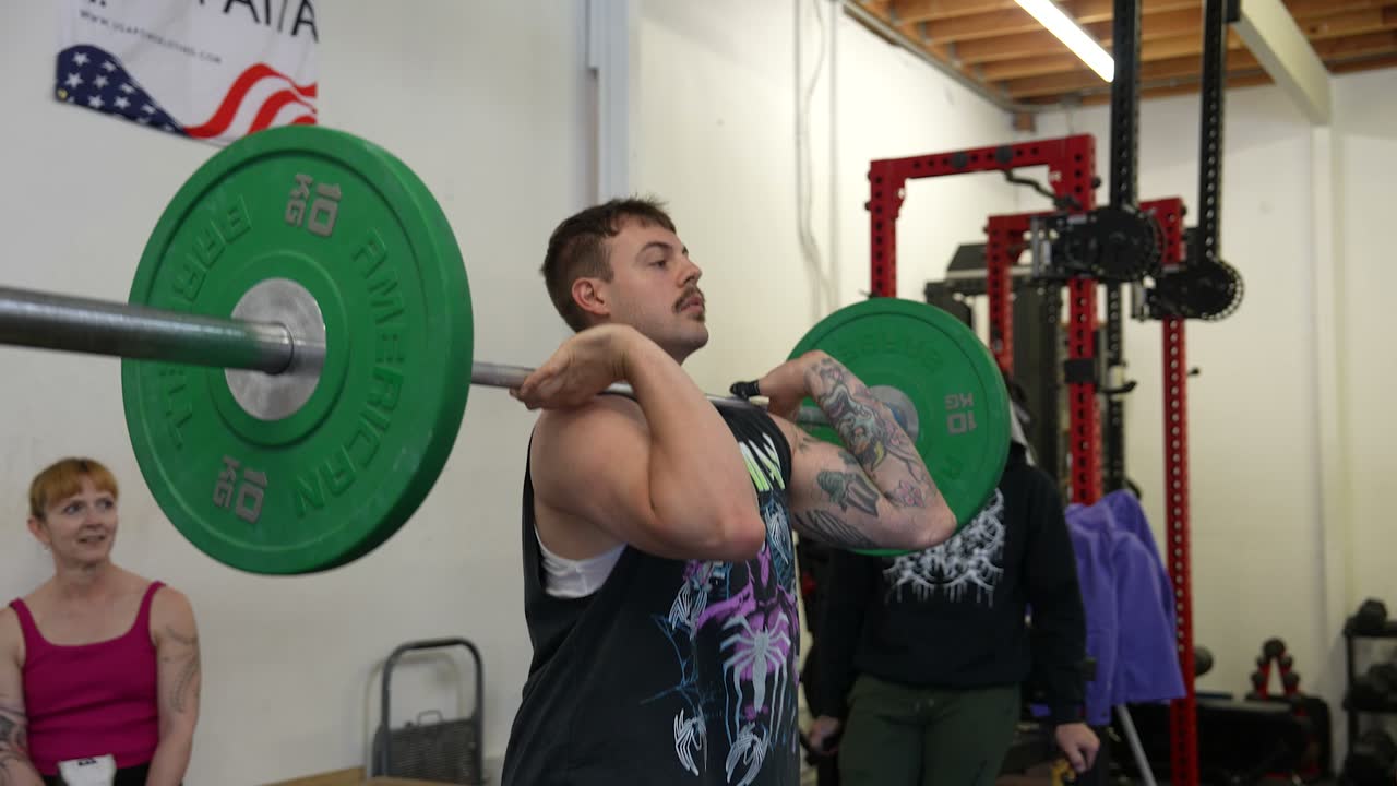 A coach talking an athlete through a lift between sets.